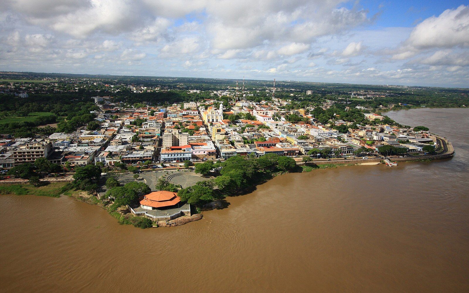Aerial view of Ciudad Bolívar's riverside buildings along a bend in the muddy Orinoco River
